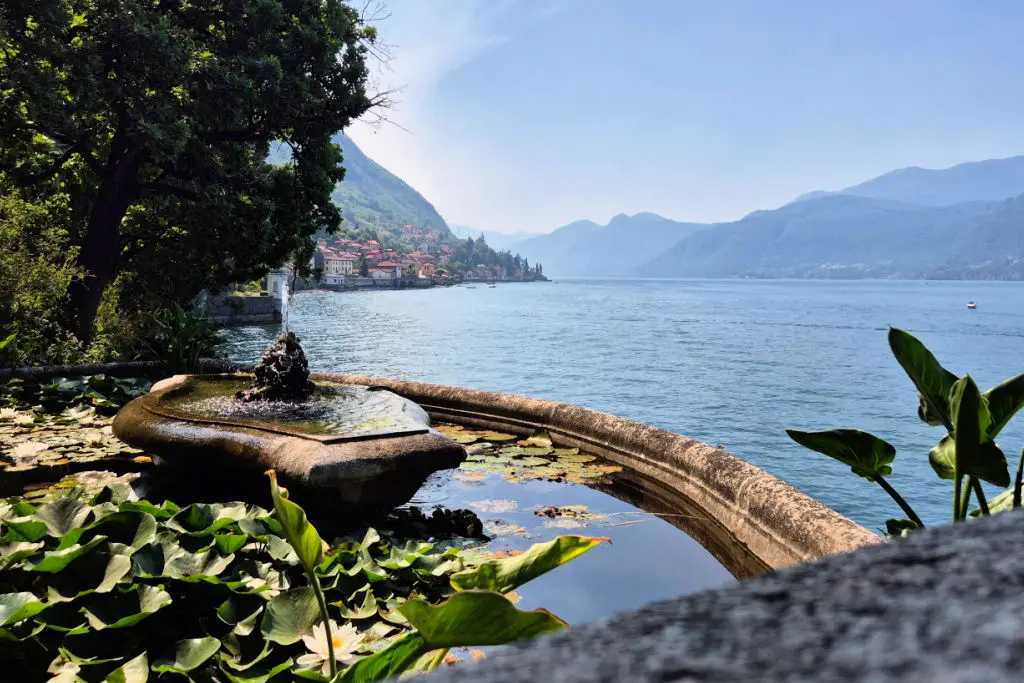 Stone fountain overlooking Lake Como with Alpine mountains in background